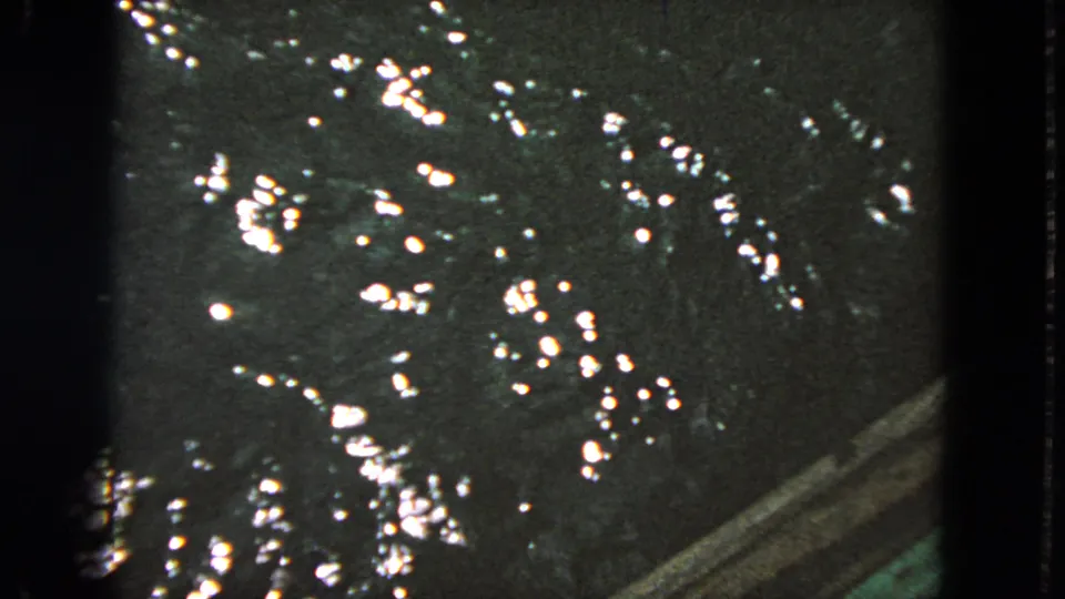 1963 San Francisco 8mm frame showing dark reflective water, clustered highlights, and a slanted edge near the lower right.