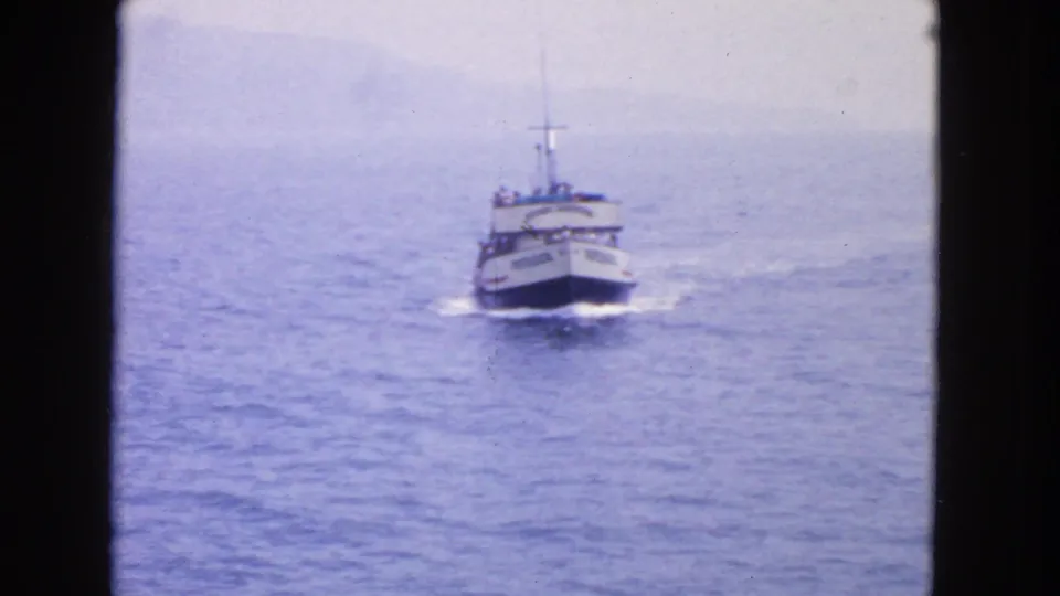 1963 San Francisco-area home-movie frame showing the Voyager passenger boat approaching across calm blue water.