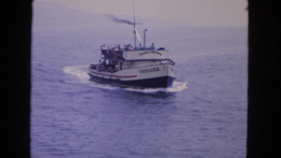 1963 home-movie frame of the Voyager passenger boat on open water near San Francisco, with riders visible on both decks.