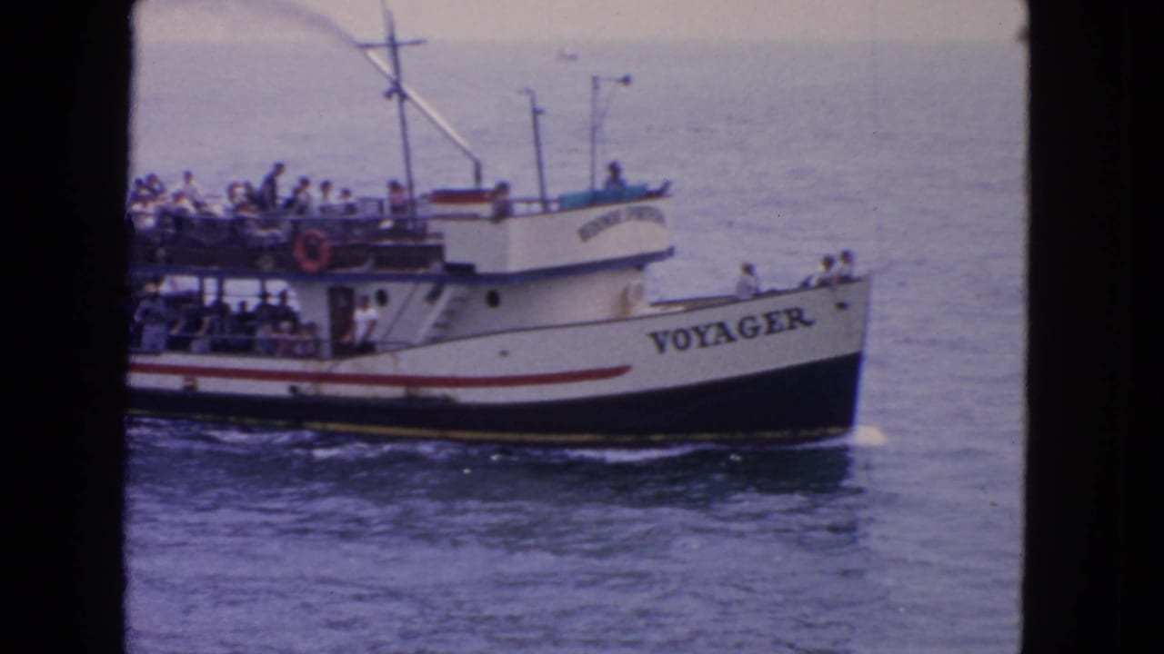 1963 San Francisco frame of Voyager broadside on the water, with passengers visible along the rails and upper observation deck.
