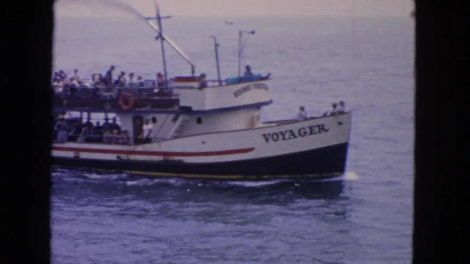 1963 San Francisco frame of Voyager broadside on the water, with passengers visible along the rails and upper observation deck.