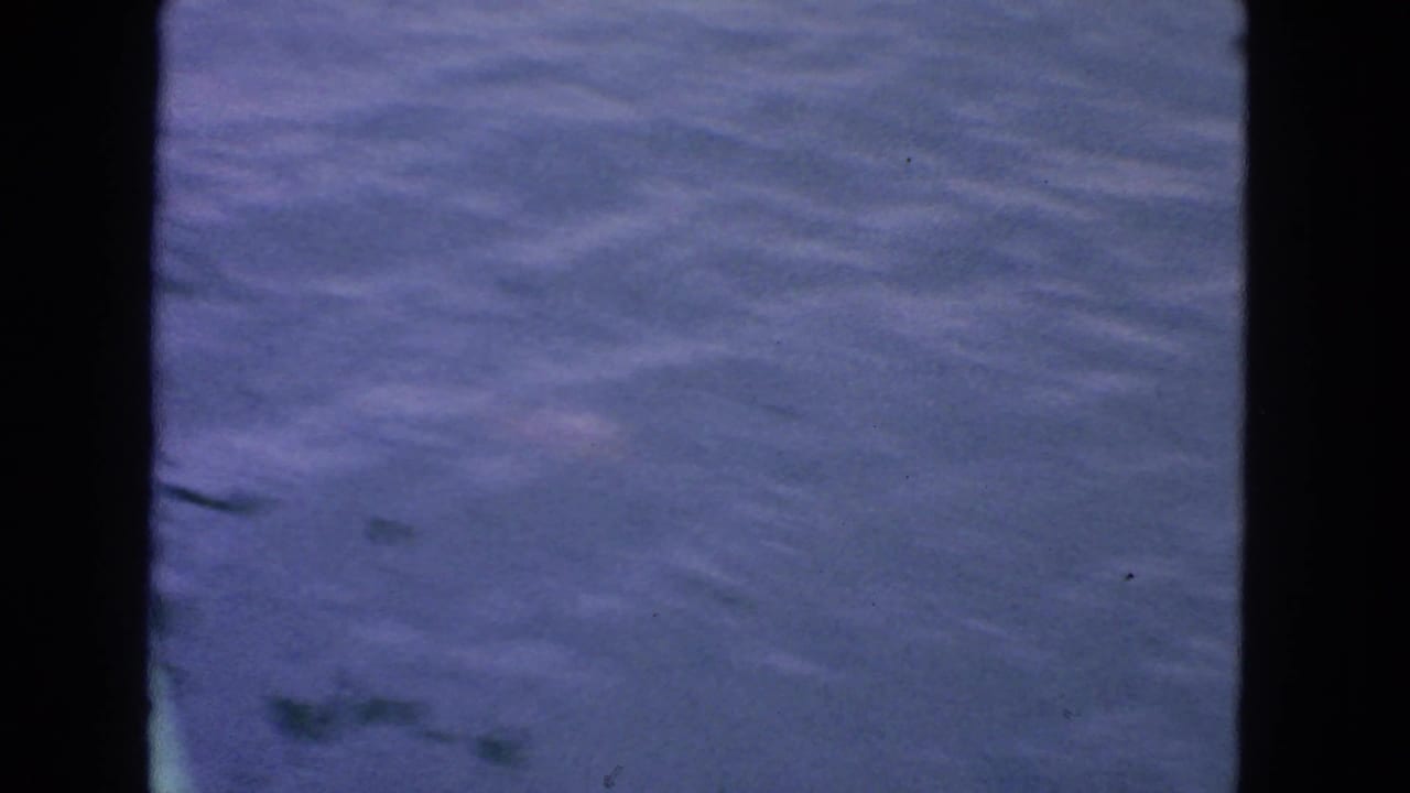 Calm rippling water bordered by a dark vertical structure.