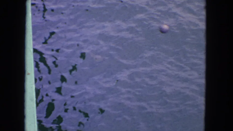 1963 8mm home-movie frame from the San Francisco area showing a green boat rail above rippling water.