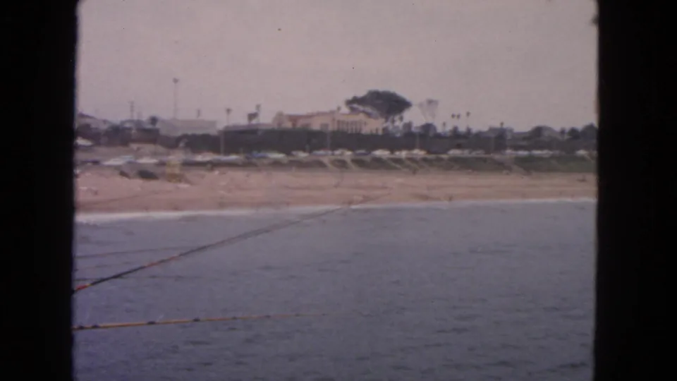 1963 San Francisco 8mm view across water toward a sandy shoreline with low houses and trees.