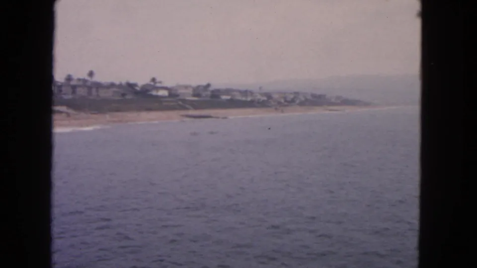 1963 San Francisco home-movie frame looking across open water to a sandy coastal neighborhood.