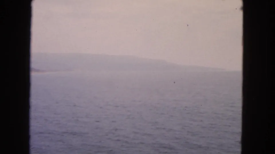 Soft 8mm footage from 1963 shows bay water and a faint San Francisco-area shoreline through a dark vessel-window divider.