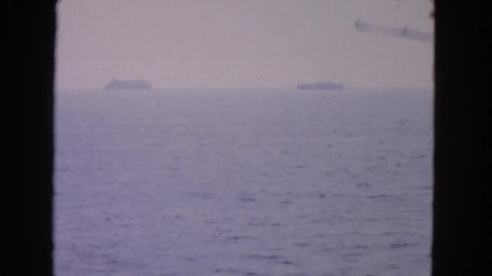 A 1963 San Francisco Bay view shows distant ships on the horizon beyond calm water, framed by dark vessel-window borders.