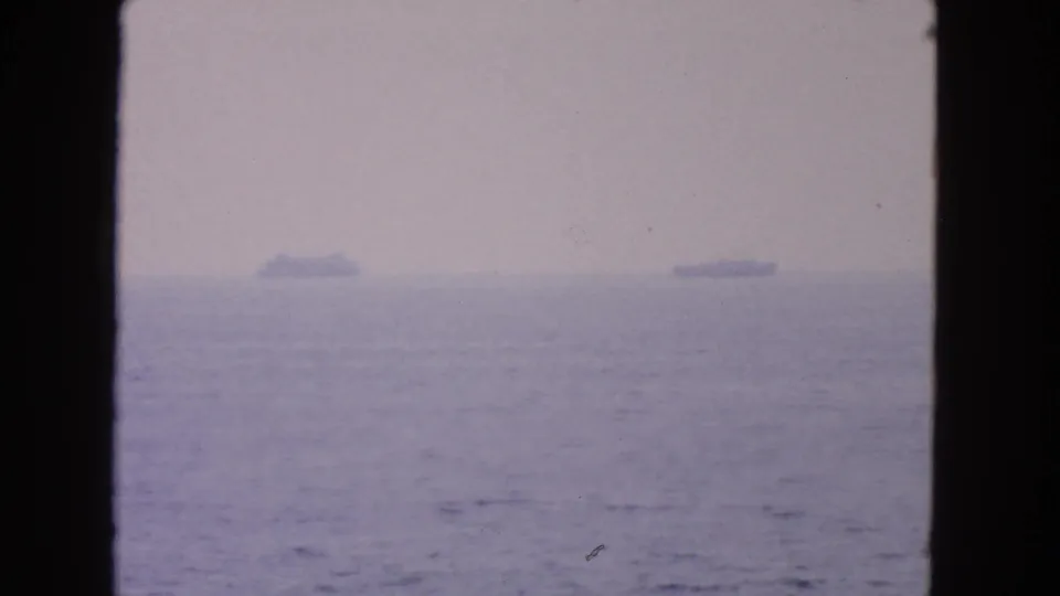 1963 8mm home-movie still showing two distant ships on a soft, purple-tinged ocean horizon near San Francisco.
