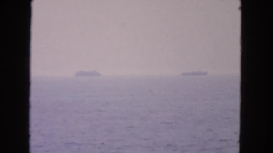 Blurred 1963 San Francisco-area 8mm frame of distant ship silhouettes on a calm ocean horizon.