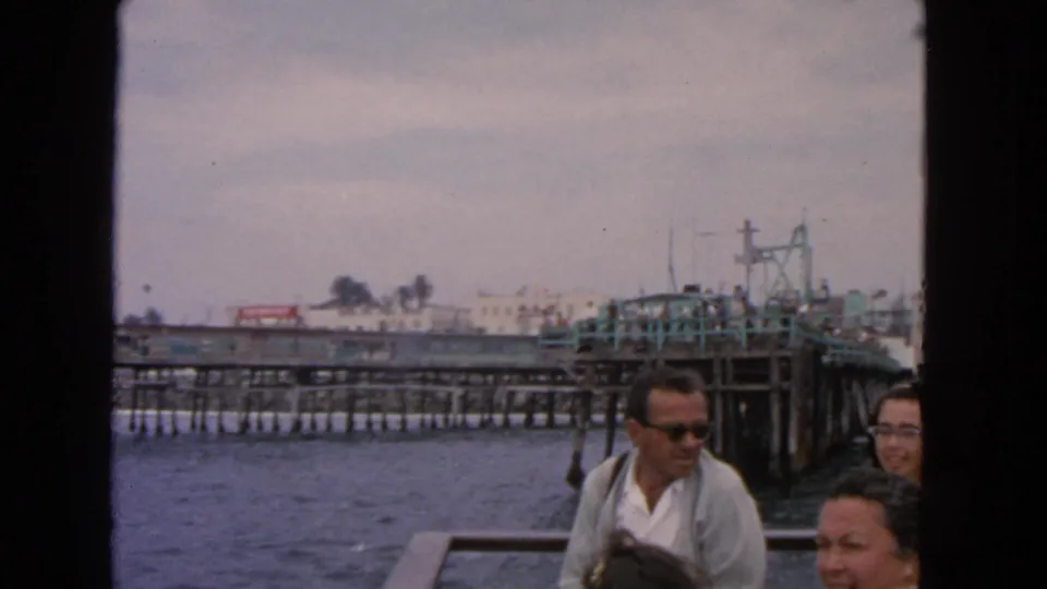 Adults on a boat ride near a San Francisco pier in 1963, with choppy water and waterfront structures in view.
