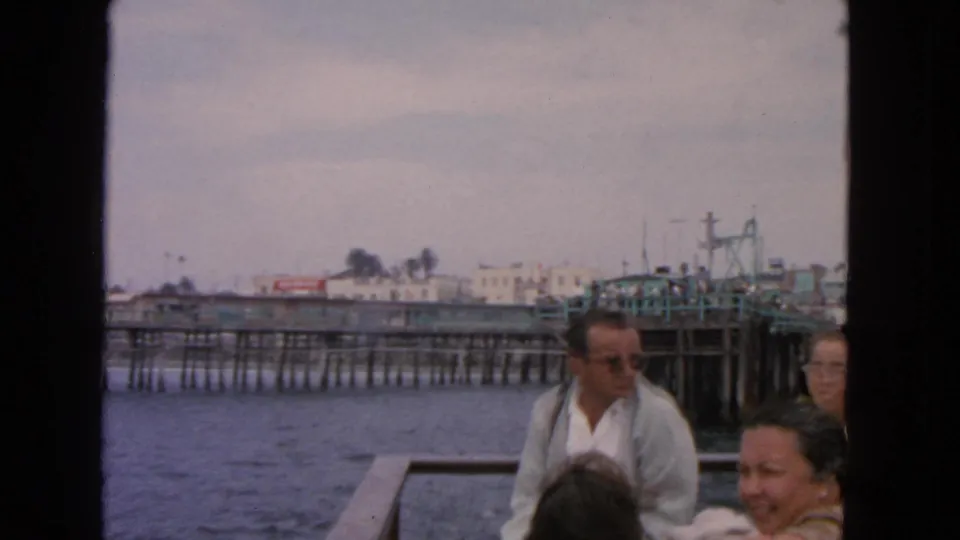 Home-movie view of boat passengers near a San Francisco waterfront pier, with visible film grain and soft color.