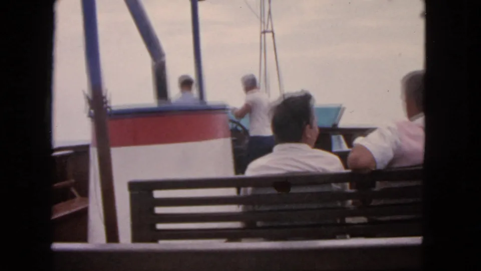 1963 San Francisco onboard frame with seated passengers and a standing man near the side rail, filmed in faded 8mm color.