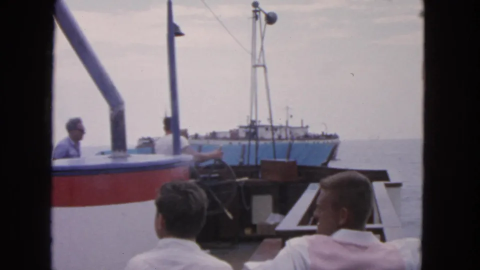 1963 San Francisco boating footage with seated men in the foreground and a larger blue-and-white vessel ahead.