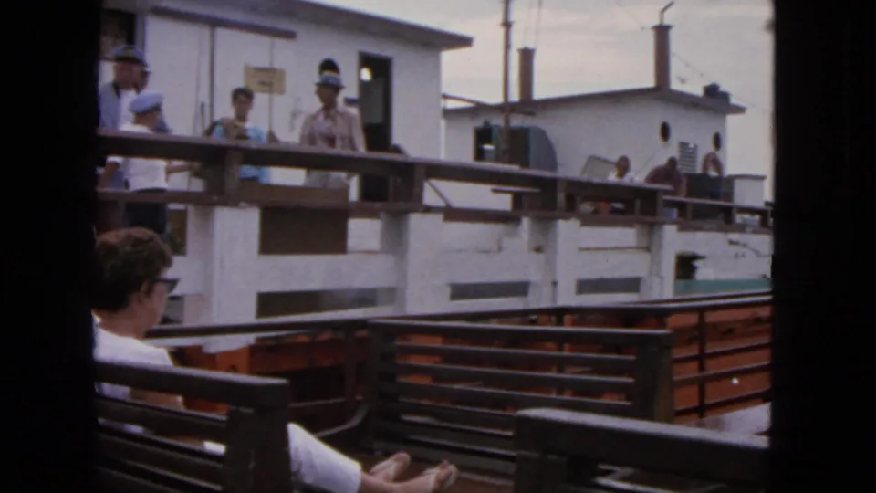 1963 San Francisco harbor deck scene with passengers near a white cabin, wood benches, railings, and another vessel alongside.
