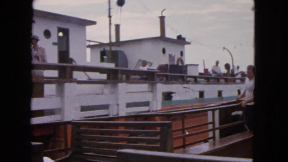 1963 San Francisco 8mm frame showing adjacent passenger boats, white cabins, deck railings, and adults standing outside.