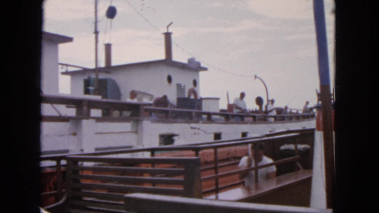 Adjacent boat deck with passengers near railings, white cabin walls, and poles overhead.