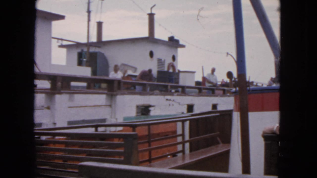 A white and red vessel fills the frame with several people visible along the upper deck.