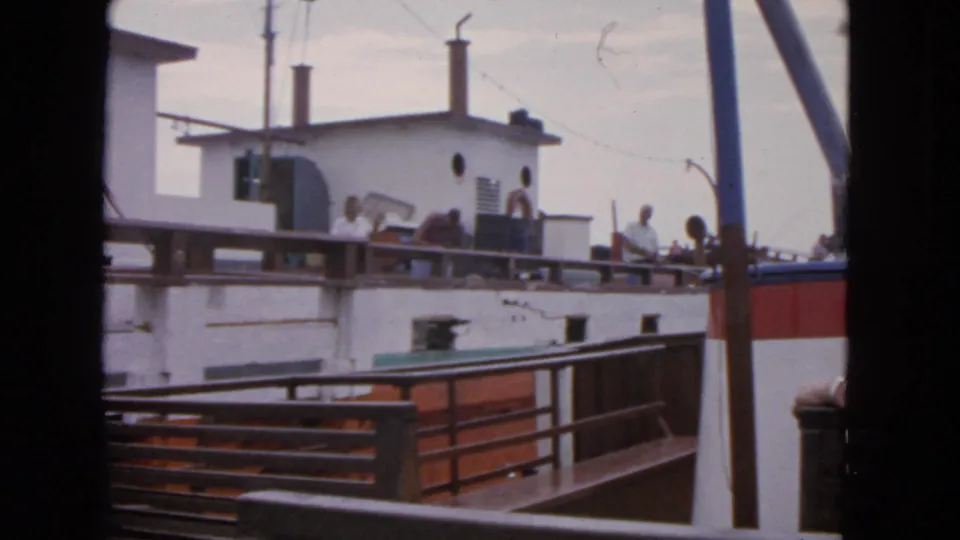 Passengers gather along the rail of a white and red vessel in a 1963 San Francisco 8mm home-movie view from the water.