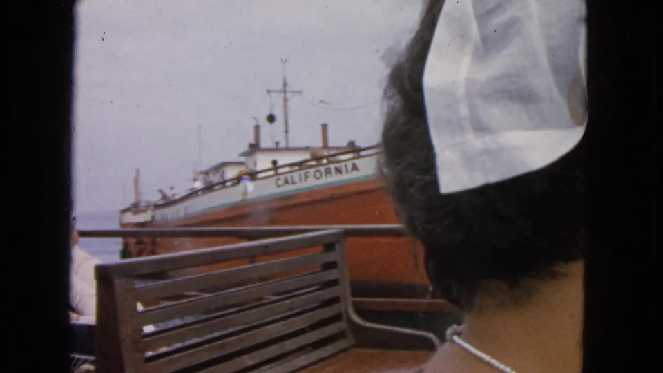 1963 San Francisco harbor travel frame with a seated woman in a white headscarf and the CALIFORNIA vessel visible behind her.