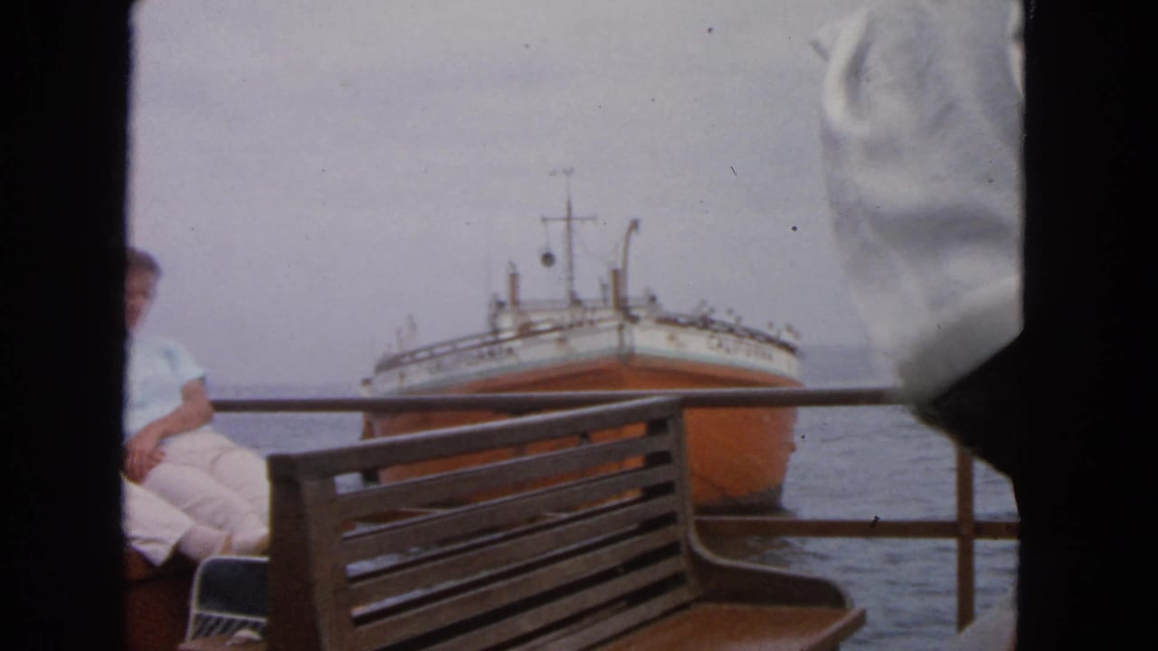 1963 San Francisco Bay view from a boat deck, showing the ship CALIFORNIA behind railing and a partly visible seated passenger.