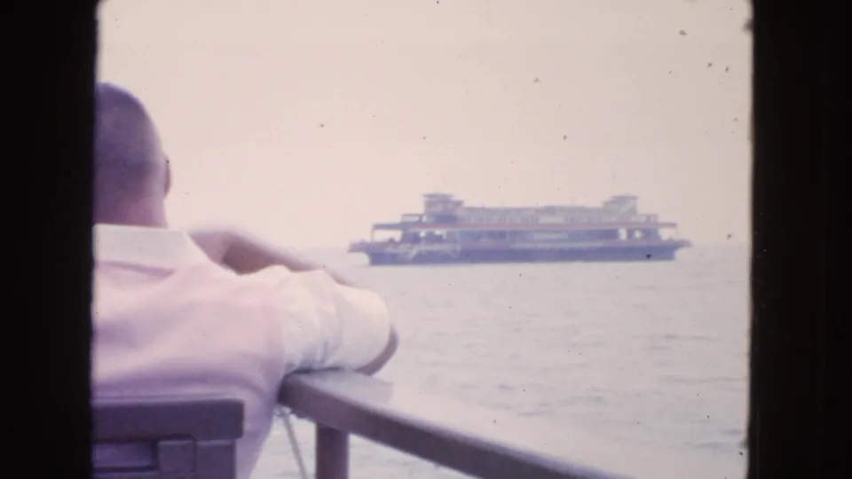 1963 San Francisco Bay home-movie view over a passenger's shoulder toward a ferry crossing hazy open water.