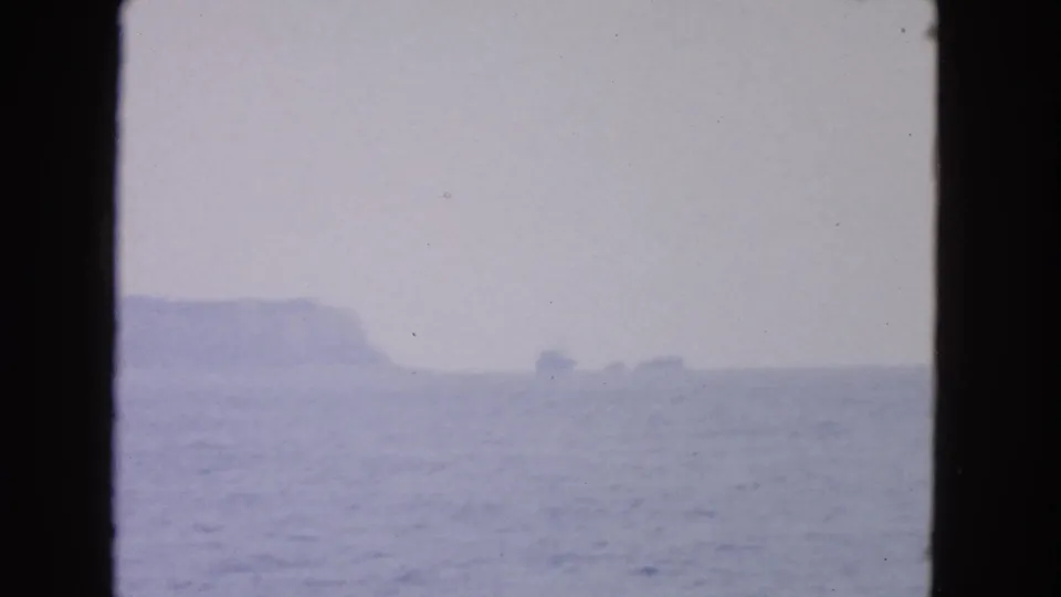 1963 San Francisco-area 8mm frame showing choppy water, misty rocks, and an overcast horizon from a vessel.