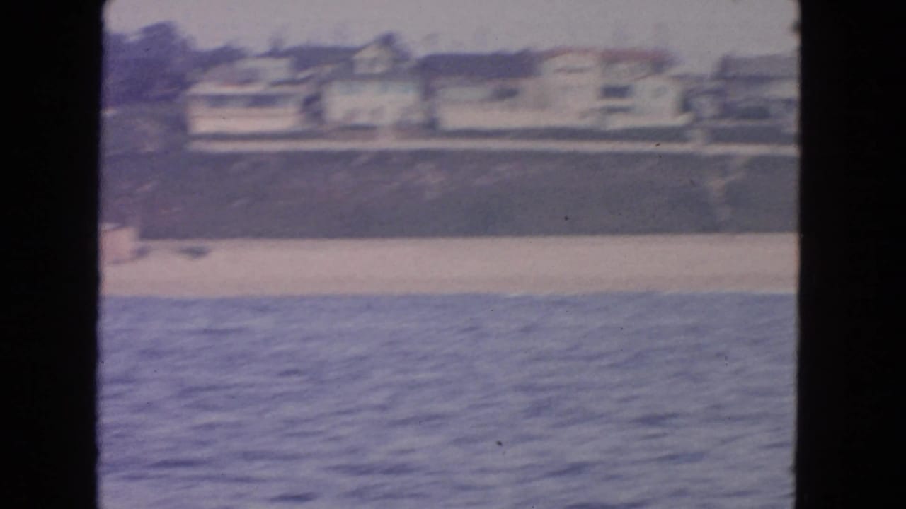 1963 8mm view from the water toward a San Francisco beach with residential buildings on the bluff.