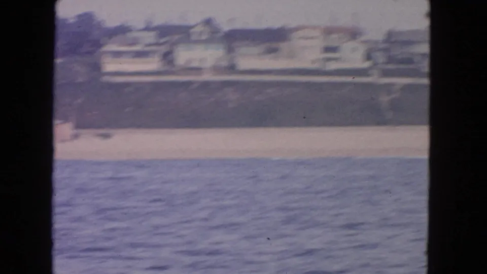 1963 8mm view from the water toward a San Francisco beach with residential buildings on the bluff.