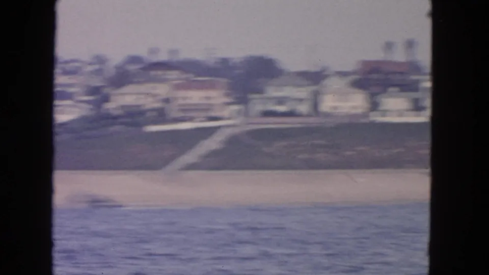 San Francisco shoreline seen from the water, with a sandy beach, hillside houses, and a diagonal beach access path.