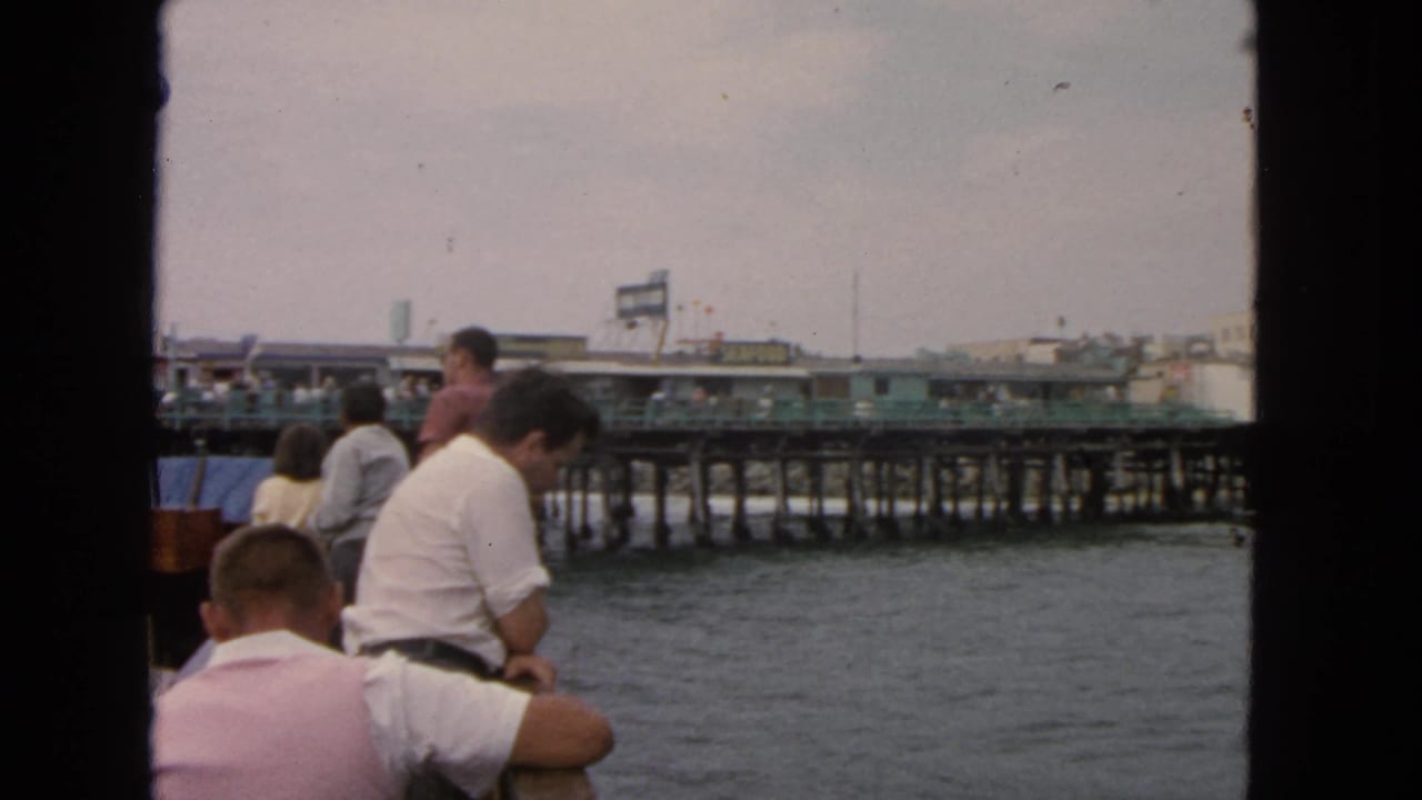 1963 San Francisco boat view with passengers at the railing and a long pier extending across the water.