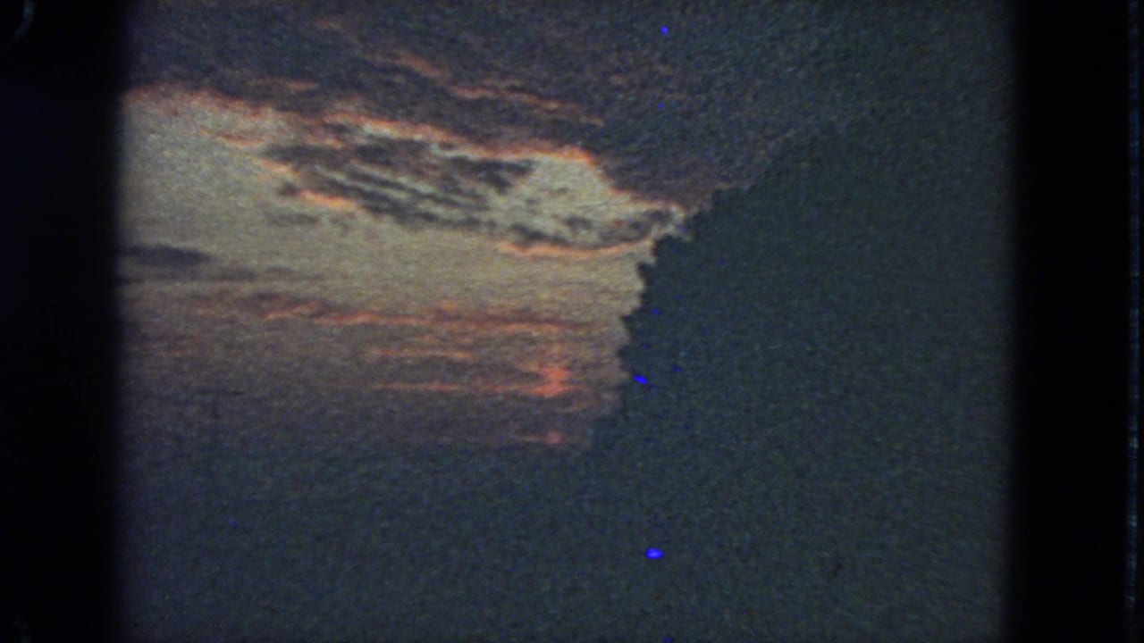 1963 San Francisco 8mm frame with a muted sunset sky, cloud layers, and a dark right-side silhouette.