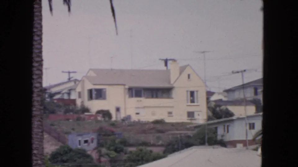 1963 San Francisco hillside residential frame with a light house, palm trunk, antennas, utility poles, and rooftops.