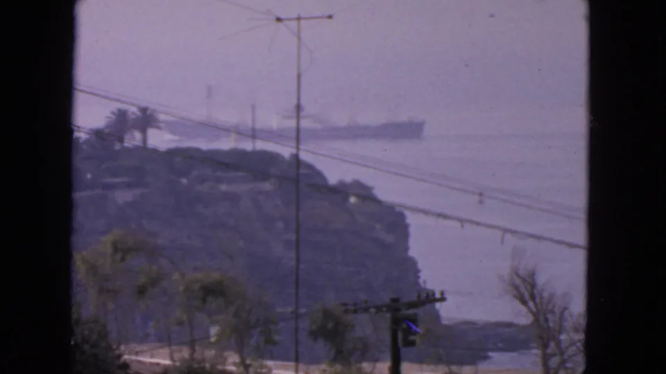 Final frame of the 1963 San Francisco coastal shot, with the liner beyond the island and foreground lines cutting across the view.