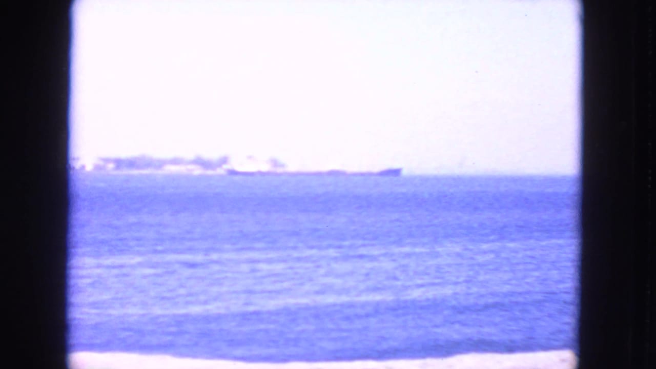 Distant ships on a blue sea with pale sky and dark 8mm frame borders.