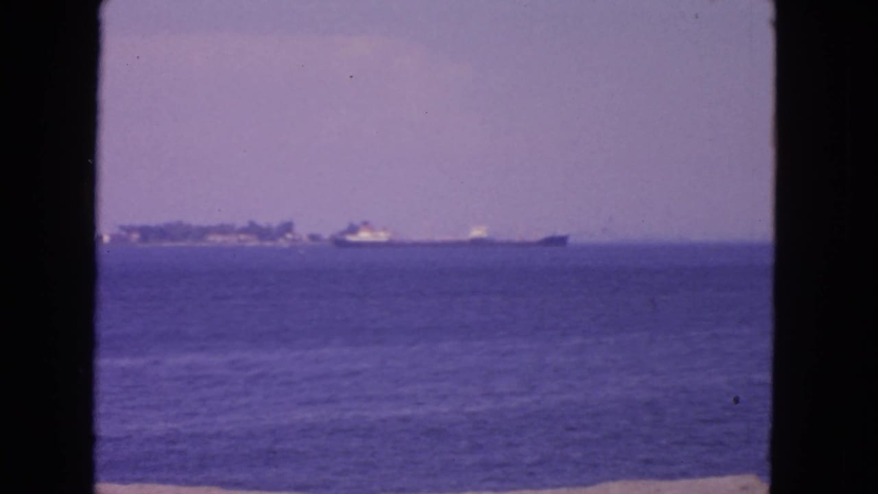 1963 San Francisco Bay frame with a distant large vessel and hazy shoreline seen from across the water.