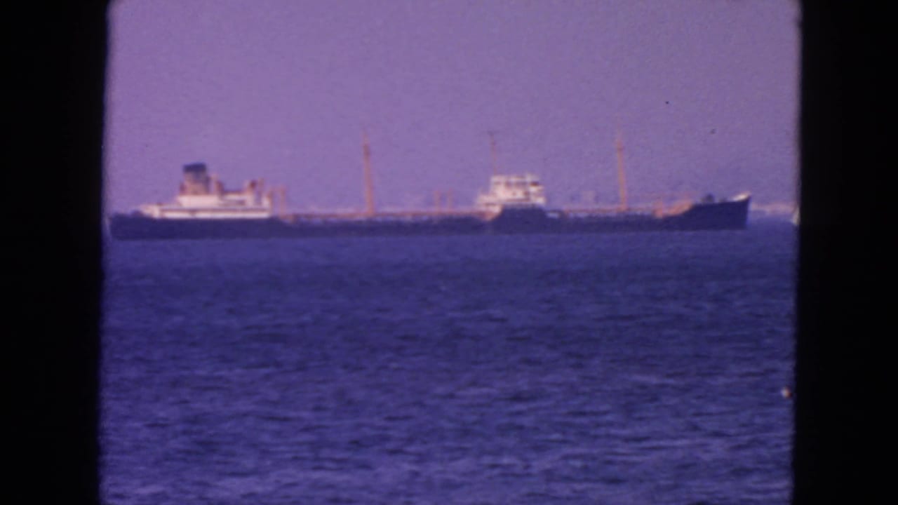 Distant tanker on San Francisco Bay in 1963, with rippled water foreground and visible 8mm frame edges.