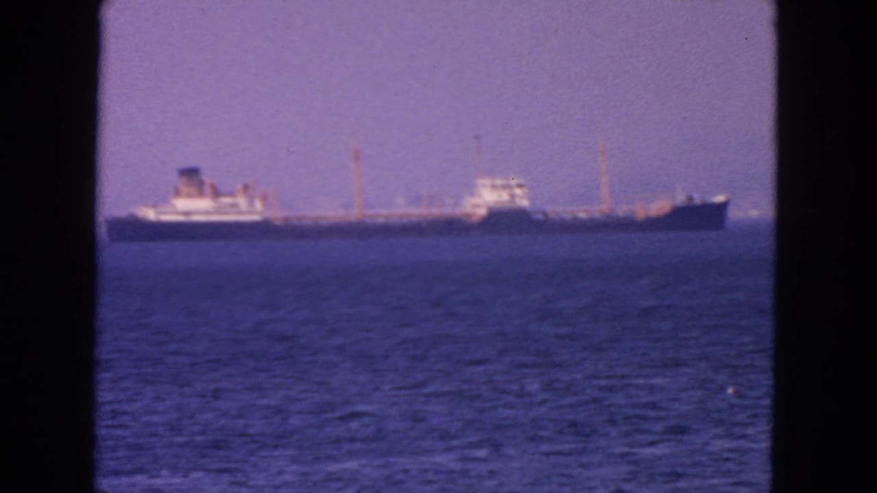 1963 San Francisco home-movie view of a distant cargo ship on calm blue bay water under a hazy sky.