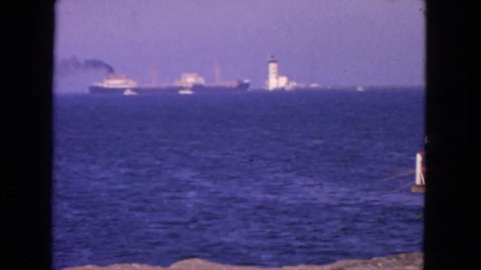 1963 San Francisco coastal frame showing a cargo ship and lighthouse-like tower in the distance across the bay.