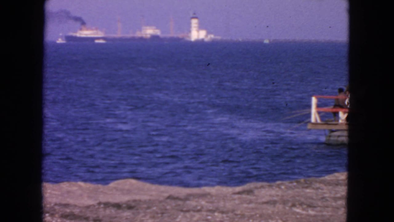 San Francisco shoreline footage from 1963 showing water, distant vessels, a white tower-like lighthouse, and a person watching from a pier.