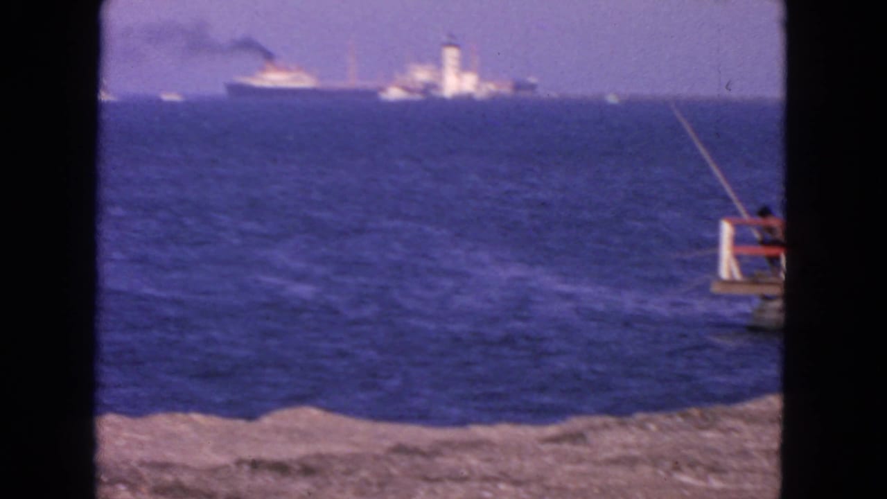 Ocean horizon with a distant ship and tower, plus part of a small fishing pier at right.