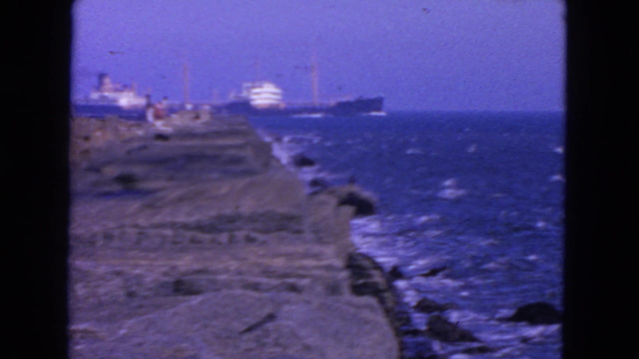 Rock jetty and ocean with distant ships near the horizon.