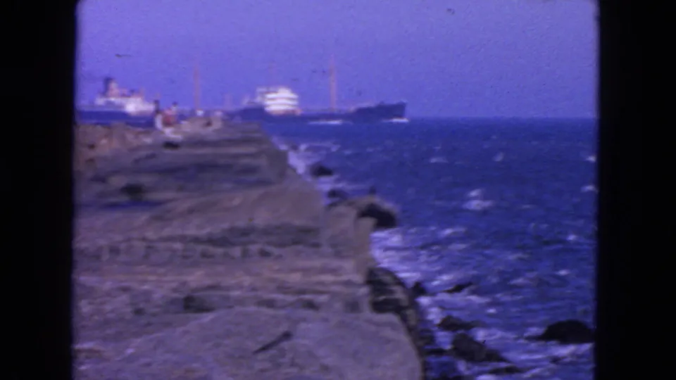 1963 San Francisco coastal view showing a rocky jetty, choppy water, and ships offshore.
