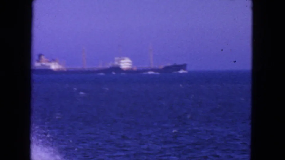 Soft 8mm frame from the 1963 San Francisco clip showing the ship farther out across blue water with surf at the lower edge.