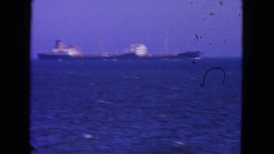 Final 1963 San Francisco frame showing a distant large ship crossing open water beneath a hazy sky, with visible 8mm dust and softness.
