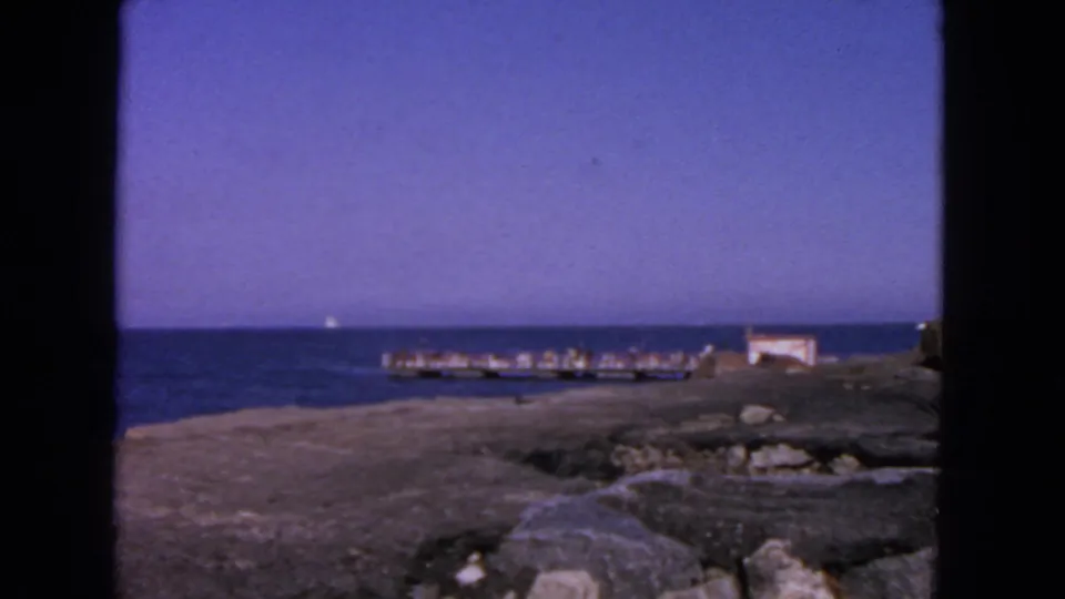 San Francisco-area coastal view with rocks, open water, and a small pier or dock under a clear blue sky.
