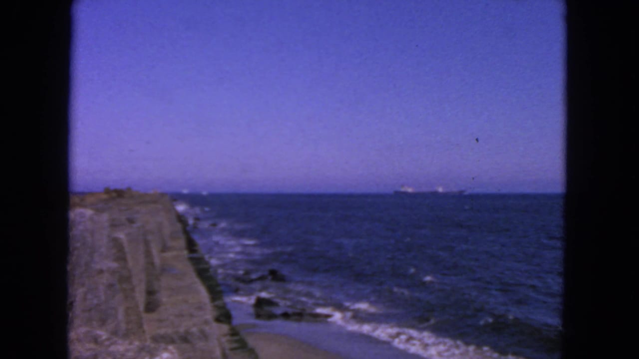Ocean horizon and breakwater with surf curling along the shoreline.
