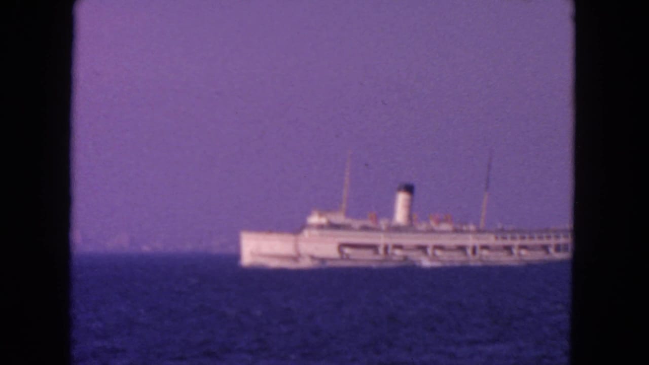 Distant white ship partly framed on the right over blue water and haze.