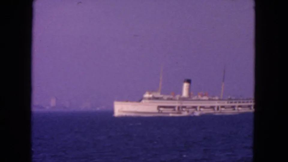 1963 San Francisco-area 8mm frame showing the white ship against blue water and a faint hazy shoreline.