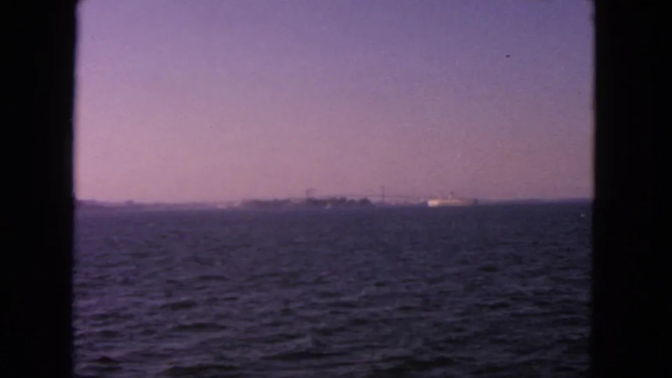 1963 San Francisco Bay water view after the ship has moved out of frame, with a low hazy shoreline in the distance.