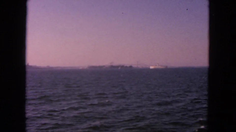 1963 San Francisco Bay home-movie frame showing open water, a distant ship, and a hazy horizon through dark frame borders.